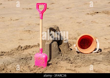 Stilleben am Meer, Eimer und Schaufel neben einem Sandburg des Kindes Stockfoto