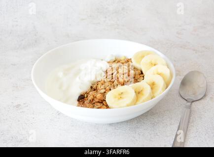 eine Nahaufnahme einer gesunden Frühstücksschüssel mit Joghurt, Granola und Bananenscheiben Stockfoto