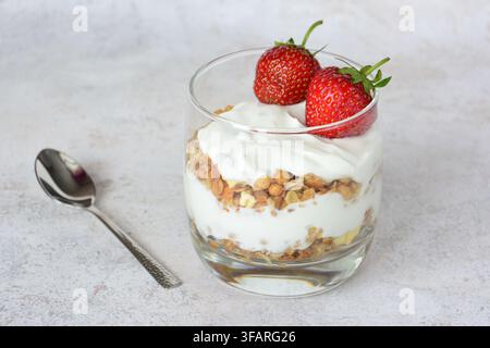 Gesunder Joghurt-Parfait mit Müsli und frischen Erdbeeren in einem Glas Stockfoto