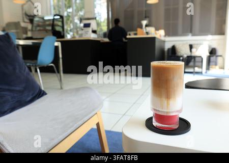 Ein Glas Eiskaffee-Latte mit Erdbeersirup auf einem gemütlichen Café-Tisch Stockfoto