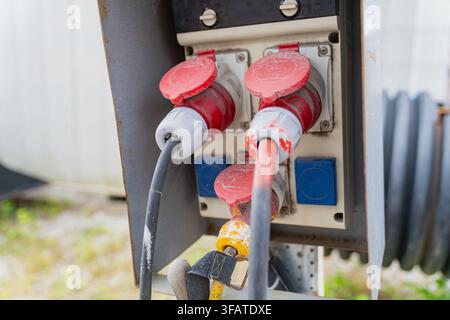 Vorübergehende Stromversorgungsanlage mit industriellen CEE-Steckverbindern und schweren Kabeln auf einer Baustelleninstallation Stockfoto