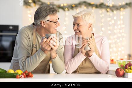 Älteres Ehepaar, Das Heiligabend Feiert, Genießt Kakao In Der Küche Stockfoto