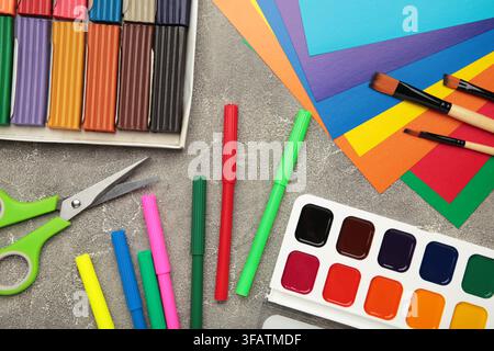 Schulbedarf Schreibwaren: Plastilin, Farbpapier, Farben auf grauem Betonhintergrund, Zurück zur Schule Konzept. Oberblick Stockfoto