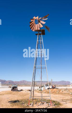 Eine vintage Metall-Windpumpe steht in der Wüstenlandschaft von Namibia Stockfoto