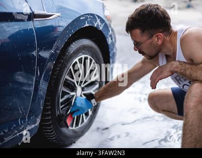 Ein Typ wäscht Autoräder mit Schaum. Stockfoto