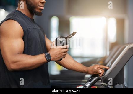 Nicht erkennbarer Sportler mit Protein-Getränk auf dem Laufband stehen Stockfoto
