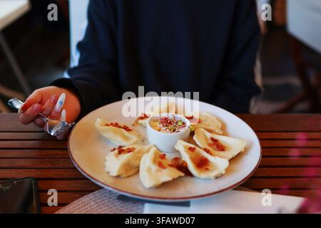 Traditionelle Pierogi-Teigwaren serviert mit knusprigem Speck und saurer Sahne auf einem Teller in einem Restaurant. Stockfoto