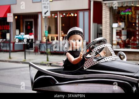 Saugerties, New York, USA - 19. Juli 2015: Künstlerische Darstellung einer Puppe, die ein altes Spielzeugauto in einer malerischen Straßenszene steuert Stockfoto