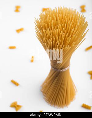 Einzelnes Bündel roher Spaghetti-Pasta, fest mit Schnur zusammengebunden, auf weißem Hintergrund stehend, Lebensmittel und Kochen. Stockfoto