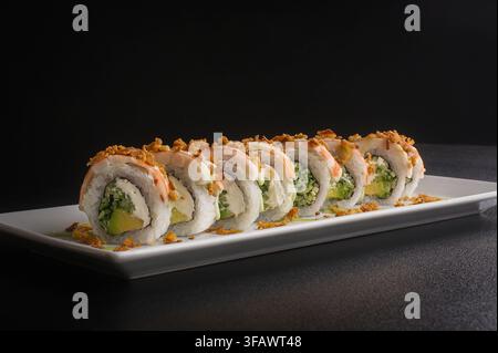 Frischer köstlicher Sushi-Rollen-Set serviert auf einer dunklen Oberfläche in einem Restaurant, Gourmet-Japan-Küche-Hintergrund für ein Speisekartenkonzept. Stockfoto