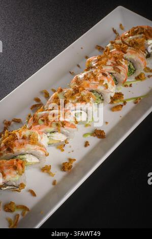 Köstliche Sushi-Rollen, garniert mit knuspriger Topping und Sauce, serviert auf einem dunklen Hintergrund, Makro-Aufnahme von oben Stockfoto