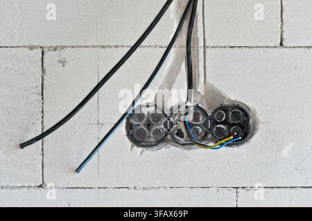 Kästen mit Kabeln für Steckdosen, die im neuen Hausgebäude mit leerer Wand installiert werden Stockfoto