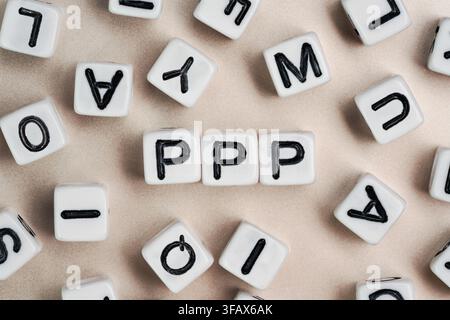 Kleine weiße und schwarze Perlenwürfel auf einem Brett, Buchstaben in der Mitte buchstabieren PPP - Praise Picture Push Stockfoto