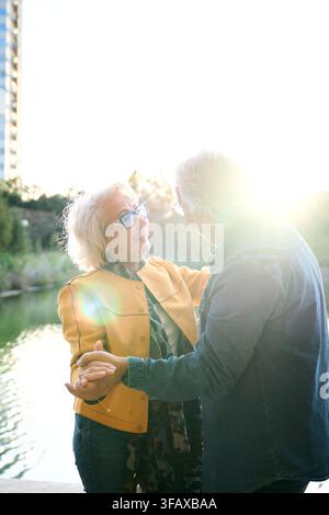 Fröhliche reife erwachsene Ehe feiert mit Tanzen und Händchenhalten mitten im See im Park der Stadt. Stockfoto