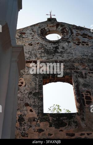 Alte Kirchenruine mit Kreuz auf der Fassade, leeres Steinfenster, blauer Himmel Stockfoto