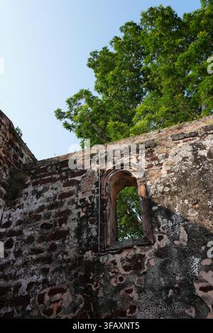 Niedriger Blick auf das Fenster des Fort Ruin Arch, grüner Baum, blauer Himmel, Malacca-Erbe Stockfoto