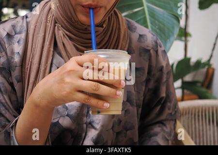 Frau trinkt Eiskaffee in einem Café am Tag Stockfoto