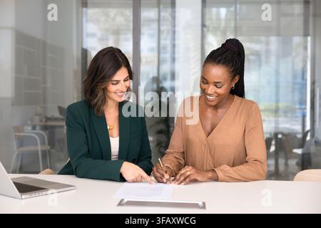 Junge afrikanische Geschäftsfrau unterzeichnet einen Vertrag bei einem Büromeeting Stockfoto