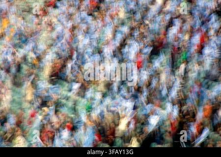 Abstrakte Bewegungsunschärfe einer farbenfrohen Menge, die im Stadion Flaggen schwenkt, energiegeladener Festival- oder Sportfan-Hintergrund. Stockfoto