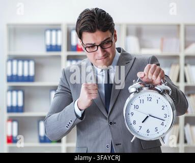 Der Geschäftsmann mit einem Wecker im Büro Stockfoto