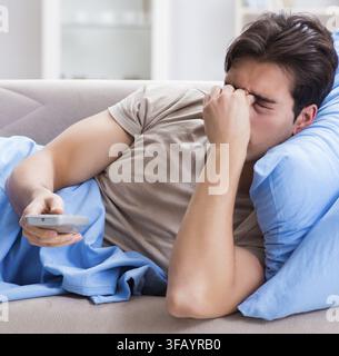 Mann schaut vom Bett weg und hält die Fernbedienung in der Hand Stockfoto