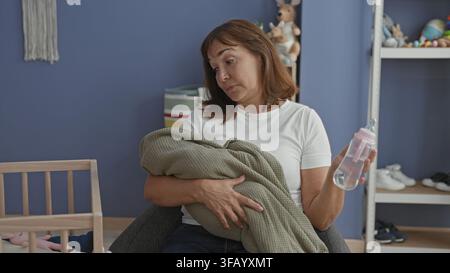 Frau, die ein eingewickeltes Baby und eine Flasche hält, Kopf nach hinten geneigt in einem Gebäude-Kinderzimmer; Müdigkeit Fürsorge Trost. Stockfoto