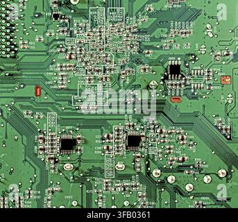 Eine detaillierte Nahaufnahme einer grünen gedruckten Schaltung, die mit Mikrochips, Widerständen und komplexen Kupferbahnen gefüllt ist und ein komplexes elektronisches Netzwerk bildet Stockfoto