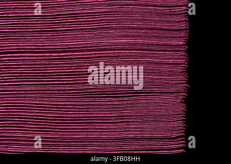 Abstrakte Textur aus geschichteten dunkelrosa Papier oder Servietten. Nahaufnahme eines horizontalen Musters aus mehreren dünnen Schichten von Magenta- oder dunkelrosa Papier, die eng gestapelt sind Stockfoto