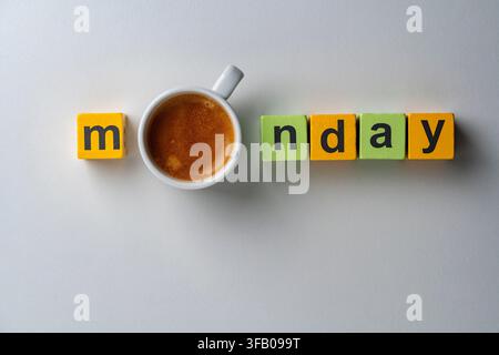 Montagmorgen-Konzept mit einer Tasse Kaffee und Holzbausteinen, Nahaufnahme. Oberblick auf das Wort Montag, das mit bunten Holzwürfeln und einer Tasse K geschrieben ist Stockfoto