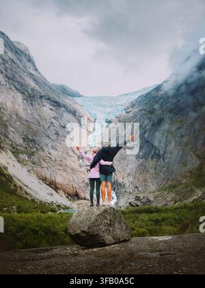 Paar umarmt sich mit Blick auf den Briksdalsbreen-Gletscher in Norwegen, Mann und Frau in Liebe reisen zusammen und genießen einen romantischen Urlaub in den Bergen, Freunde auf Hi Stockfoto