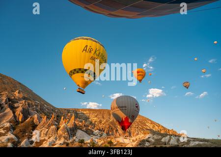Cappadocia, Türkei – 6. August 2026: Air Kapadokya-Luftballons fliegen bei Sonnenaufgang über die Felsformationen von Kappadokien Stockfoto