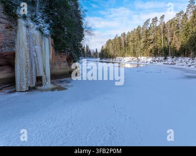 Gefrorener Wasserfall und schneebedeckter Fluss am Spriņģu-Felsen im Winter, Lettland Stockfoto