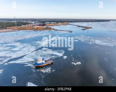 Fischereiboot zwischen Meereis im Hafen von Skulte an der Ostseeküste Lettlands Stockfoto