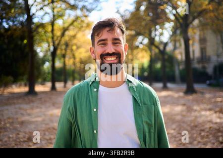 Lächelnder Mann mit Bart steht in einem Herbstpark. Stockfoto