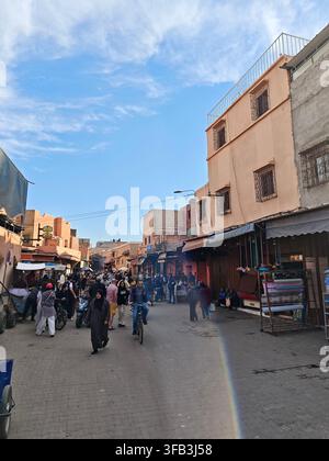 Belebte traditionelle Marktstraßen und Souks in Marrakesch, Marokko, mit Fußgängern, lokalen Geschäften, Motorrädern und traditioneller marokkanischer Architektur. Stockfoto