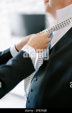 Nahaufnahme einer Person, die eine gemusterte Krawatte bindet Stockfoto