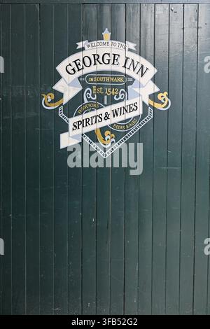 Eingangstor zum George Inn Yard, Borough High Street, Southwark, London, mit einem bemalten Schild für das historische George Inn. Stockfoto