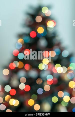 Minimale Weihnachtsbaum-Silhouette, beleuchtet von weich unscharf ausgerichteten kalt-tonigen Lichtern vor einem hellblauen Hintergrund, die eine ruhige und moderne Winterstimmung erzeugen Stockfoto