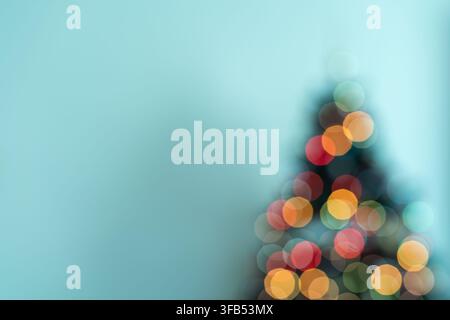 Nahaufnahme des oberen Teils einer Weihnachtsbaum-Silhouette mit wunderschön verschwommenen Lichtern vor einem weichen hellblauen Hintergrund, mit sauberem Textplatz Stockfoto