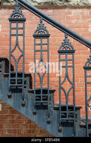 Eine speziell gestaltete schmiedeeiserne Treppe verleiht einem historischen Backsteingebäude Raffinesse. Stockfoto