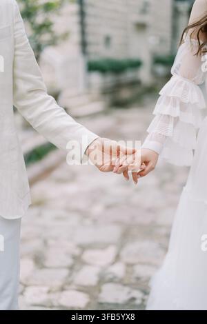 Romantischer Moment eines Paares, das sich in weißen Outfits an den Händen hält Stockfoto