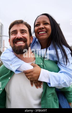 Glückliches multirassisches Paar, das draußen lächelt. Stockfoto