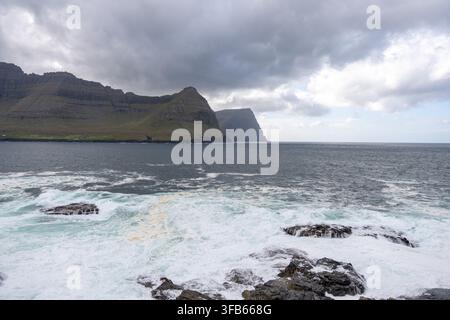 Ozeanwellen schlagen gegen das Dorf Vidareidi und die Inseln Bordoy und Kunoy im Hintergrund Stockfoto