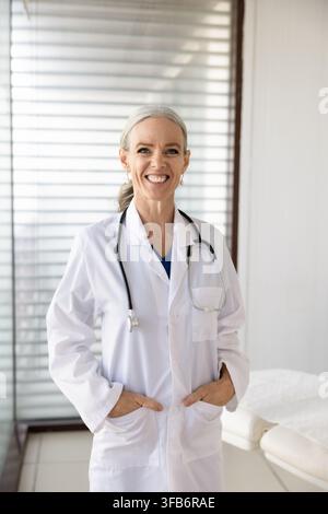 Lächelnde Ärztin mittleren Alters steht in der Klinik Stockfoto