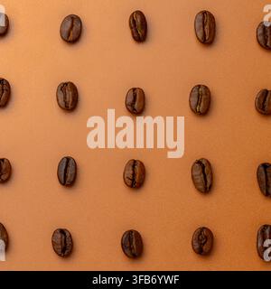 Quadratische Ausschnittdarstellung eines Flachlayouts von gerösteten Kaffeebohnen, die in einem orthogonalen Rastermuster vor einem texturierten Hintergrund angeordnet sind. Stockfoto