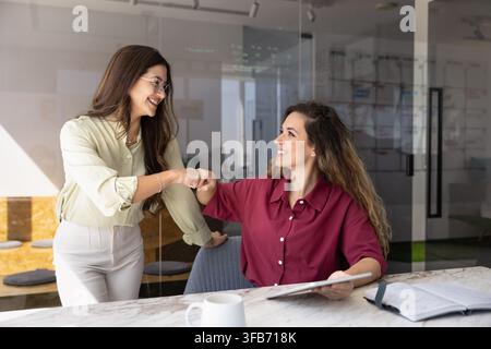 Frauenkolleginnen, die sich während eines Meetings im Büro mit dem Fauststoß begrüßen Stockfoto