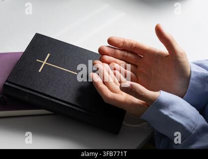 Christliche Frau betet mit offenen Händen neben der Heiligen Bibel Stockfoto
