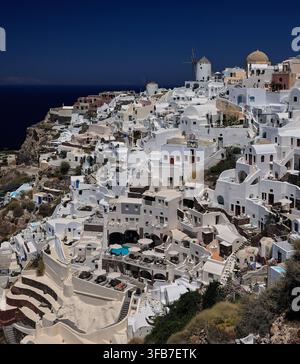 Luftaufnahme von weiß getünchten Häusern, Pools und traditionellen Windmühlen, Oia, Santorin, Griechenland Stockfoto