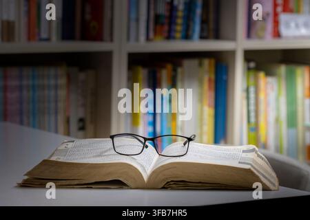 Offenes Buch mit Brille und Kaffee auf dem Schreibtisch Stockfoto