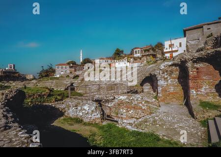 Antike römische Amphitheaterruinen mit Ziegelbögen, traditionelle Häuser am Hang dahinter. Durrës, Qark Durrës, Albanien, Europa Stockfoto
